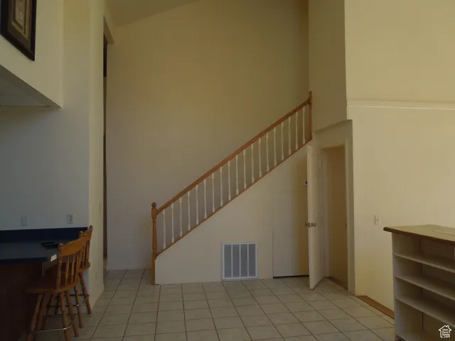 Unfurnished living room featuring stairway and tile patterned flooring