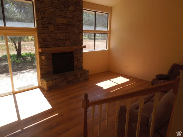 Unfurnished living room featuring wood finished floors and a stone fireplace