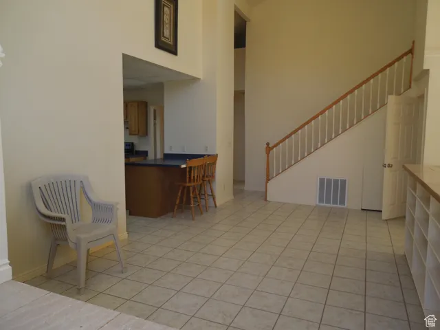 Living room featuring stairway, light tile patterned floors, and a towering ceiling
