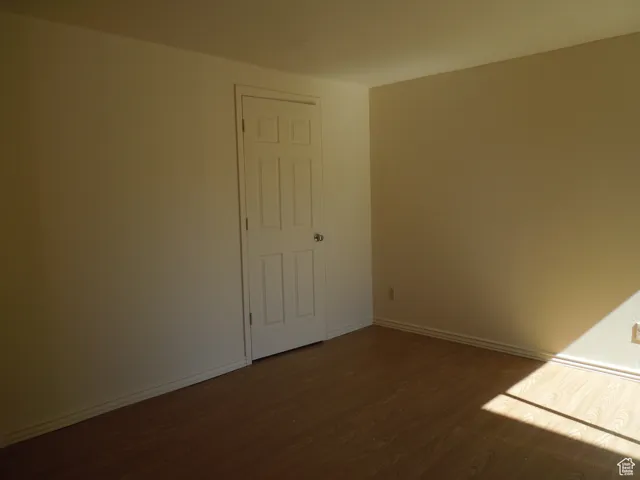 Empty room with dark wood-style flooring and baseboards