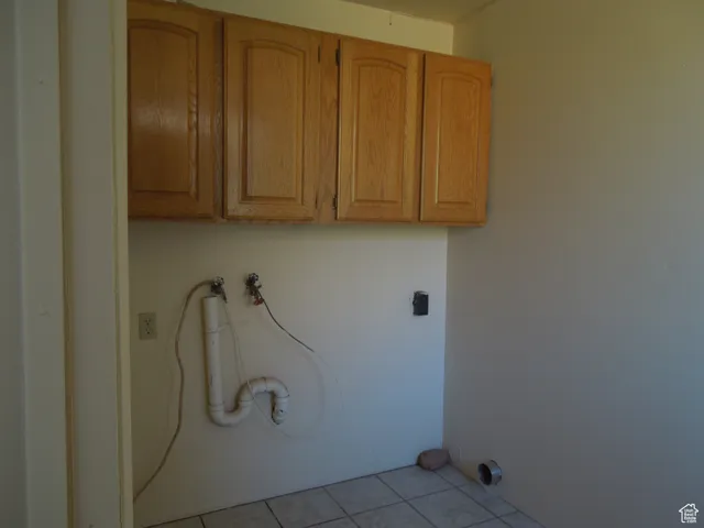 Laundry room featuring cabinet space and light tile patterned flooring