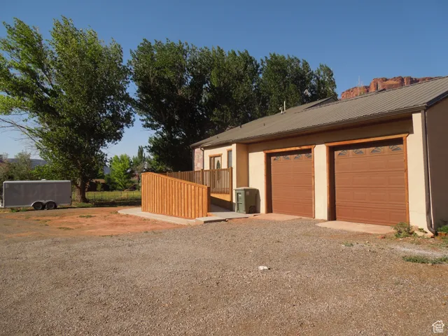 View of property exterior with stucco siding, a metal roof, dirt driveway, and a garage