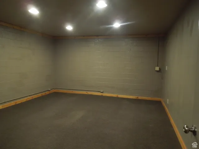 Empty room featuring carpet floors and concrete block wall