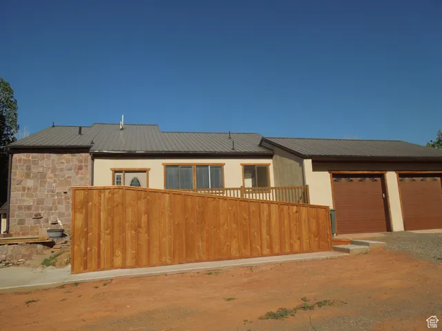 View of front of property with a metal roof, driveway, stucco siding, and an attached garage