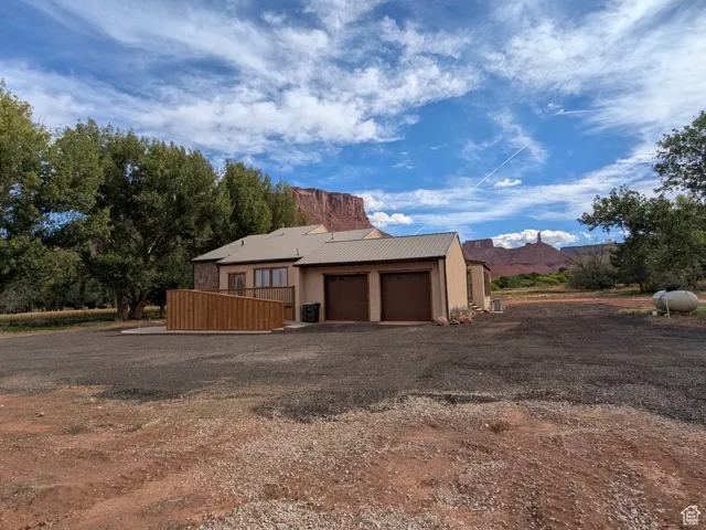 View of side of property with a mountain view, driveway, a metal roof, a garage, and stucco siding
