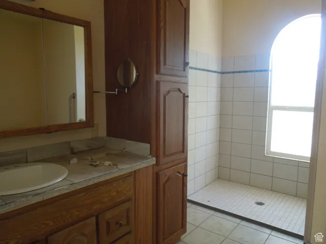 Full bath featuring vanity and tiled shower