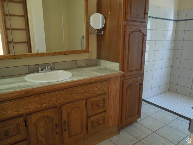 Bathroom with vanity, tile patterned floors, and tiled shower