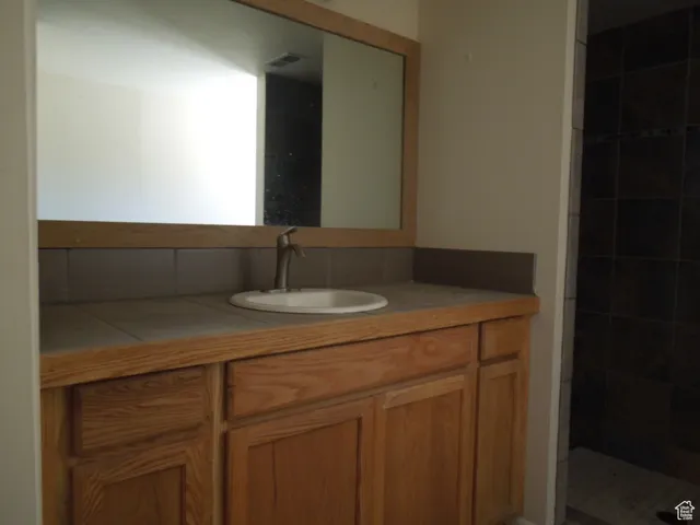 Full bath featuring vanity and tiled shower