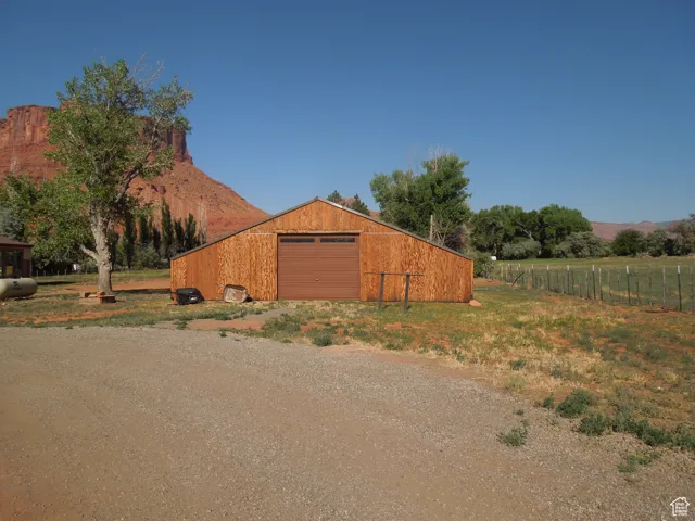 View of home's exterior with driveway, a detached garage, an outdoor structure, and a mountain view