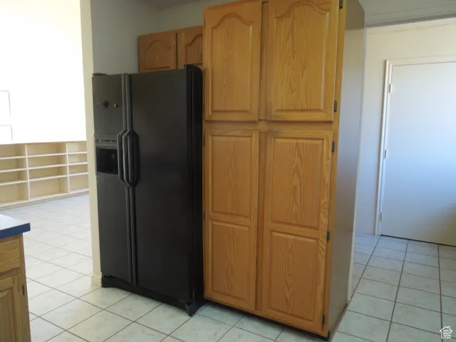 Kitchen featuring black fridge, light tile patterned flooring, and ornamental molding