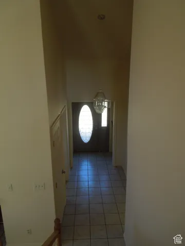 Doorway to outside with light tile patterned floors, a chandelier, and a high ceiling