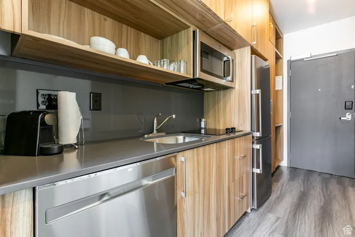 Kitchen featuring appliances with stainless steel finishes, open shelves, modern cabinets, dark wood-type flooring, and dark countertops