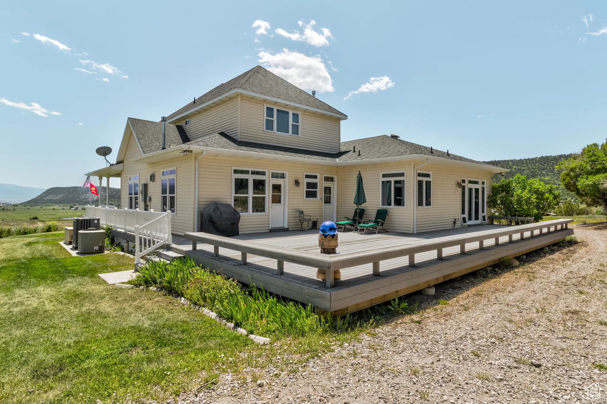 Back of house featuring a shingled roof, a wooden deck, and a yard
