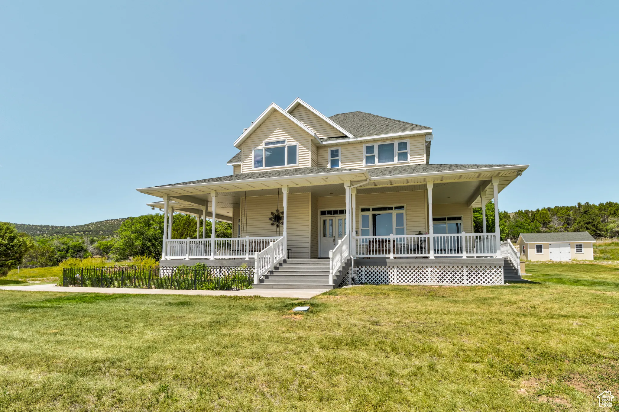 Farmhouse inspired home with covered porch, a front yard, and a shingled roof