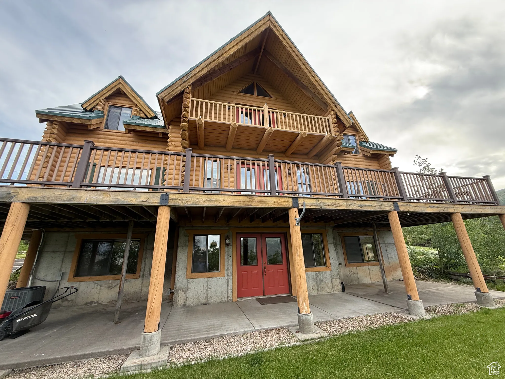 Back of house with log exterior, a patio area, and a wooden deck