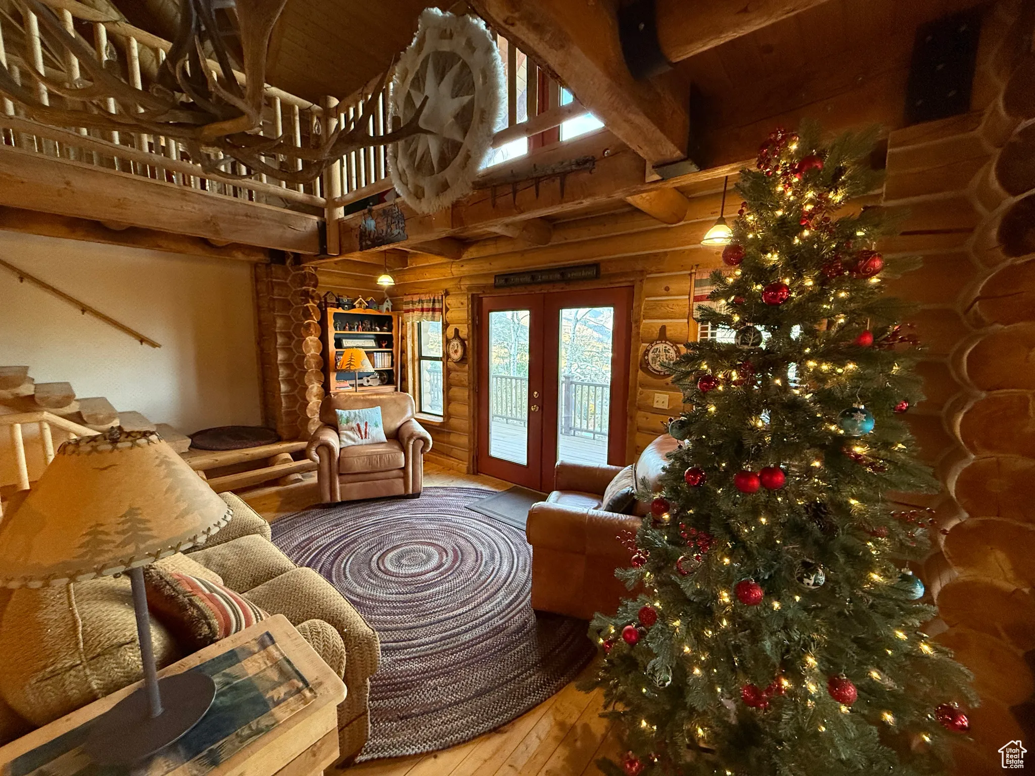 Living area with hardwood / wood-style flooring, a high ceiling, french doors, beam ceiling, and rustic walls