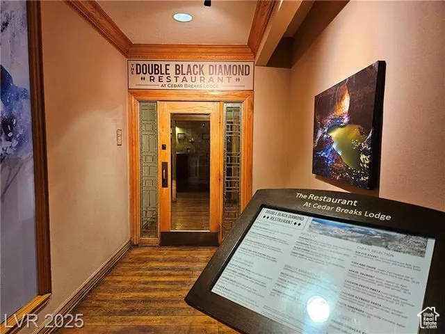 Hallway featuring ornamental molding and dark wood-style floors