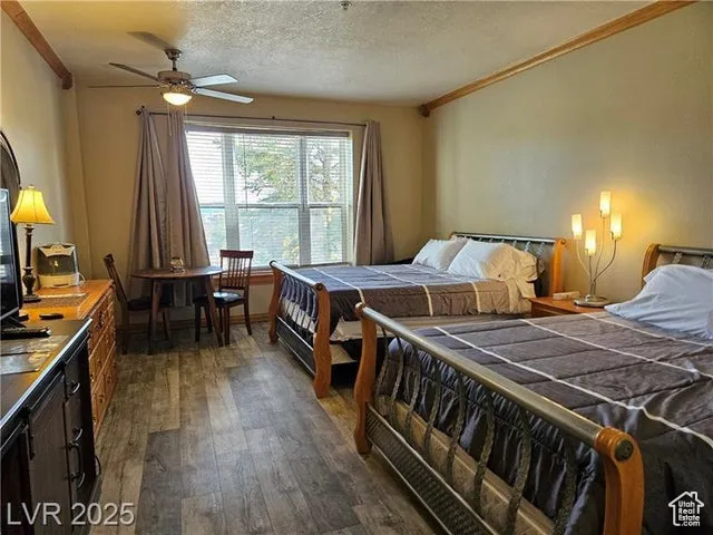 Bedroom featuring crown molding, dark wood-style floors, and a textured ceiling