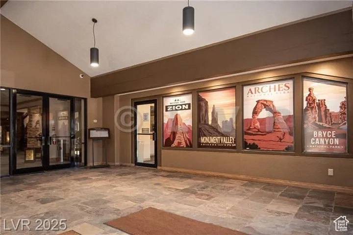 Cinema featuring stone finish flooring, high vaulted ceiling, and french doors