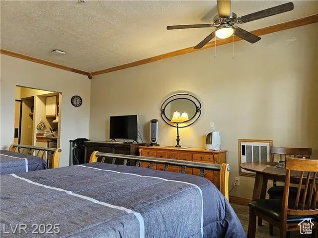 Bedroom with wood finished floors, crown molding, and a textured ceiling