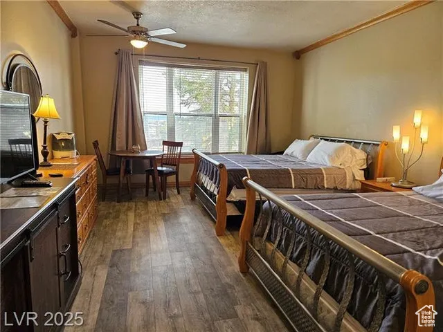 Bedroom with dark wood finished floors, crown molding, and a textured ceiling
