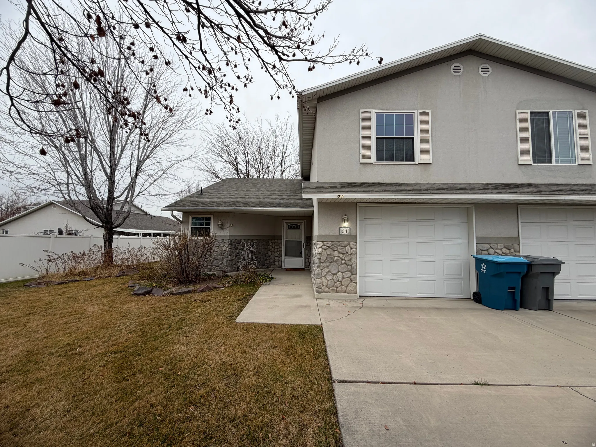 View of front of home with stone siding, a garage, concrete driveway, and stucco siding