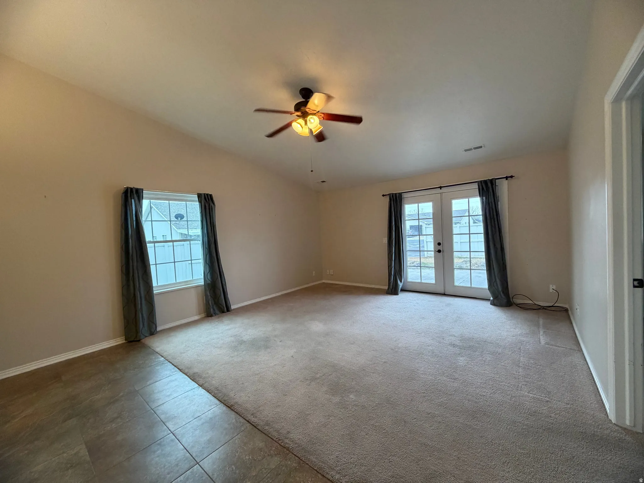 Spare room with french doors, a ceiling fan, light carpet, healthy amount of natural light, and lofted ceiling