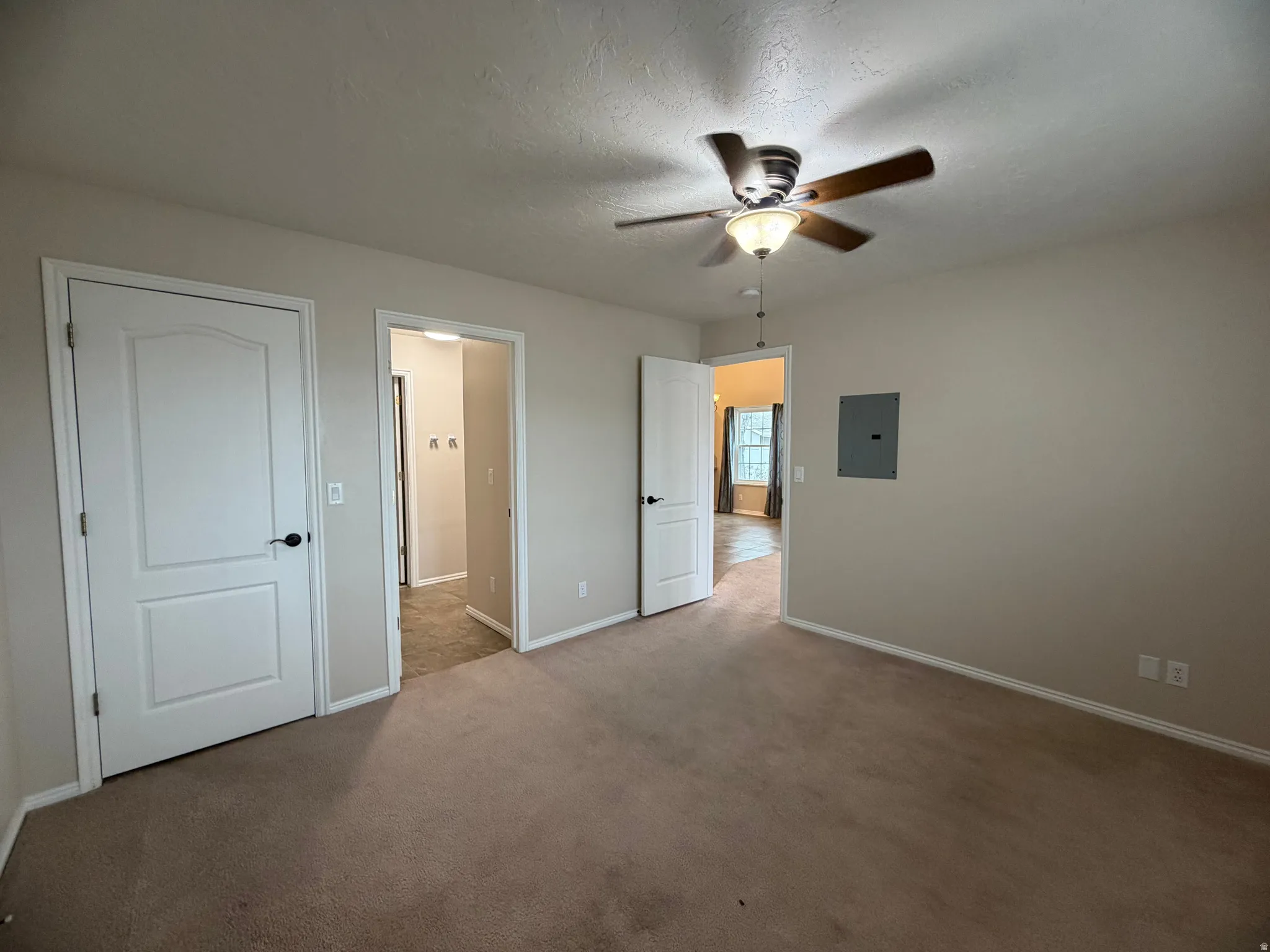 Unfurnished bedroom featuring a ceiling fan, carpet, electric panel, and a textured ceiling