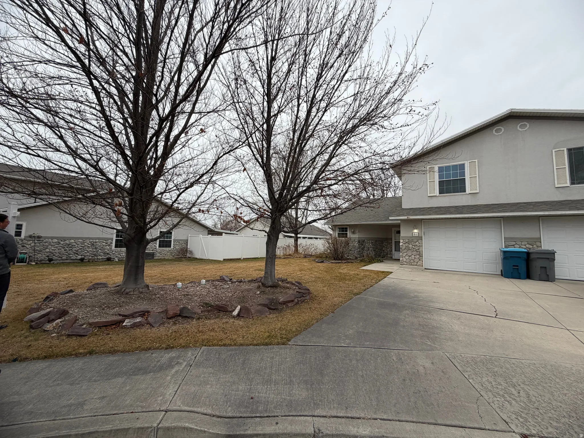 View of property exterior with driveway, an attached garage, stone siding, and stucco siding