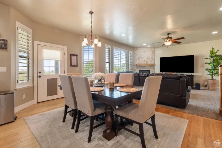 Dining room featuring healthy amount of natural light, light wood finished floors, a fireplace, recessed lighting, and a ceiling fan