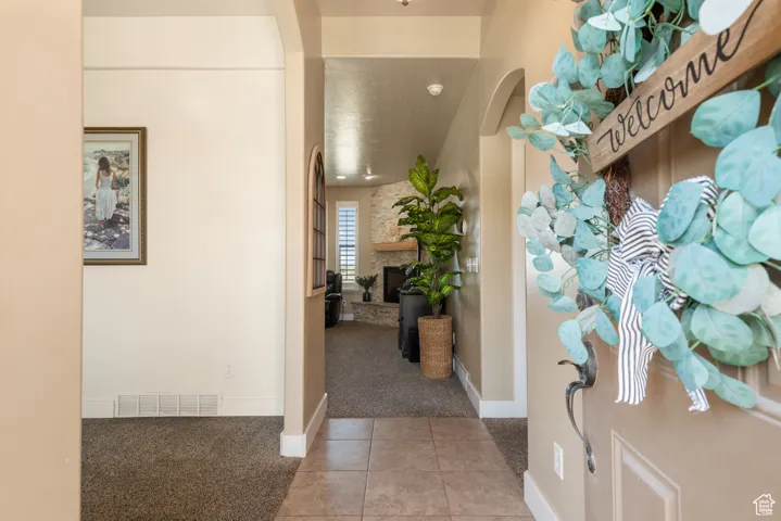 Entrance foyer featuring light colored carpet, light tile patterned flooring, arched walkways, and a fireplace