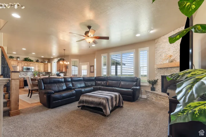 Living area featuring a fireplace, ceiling fan, recessed lighting, light colored carpet, and a textured ceiling