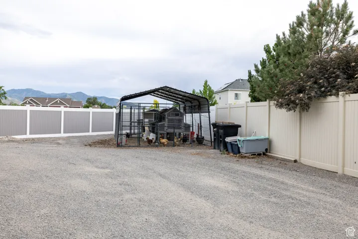 View of car parking with a fenced backyard, a mountain view, a detached carport, and exterior structure