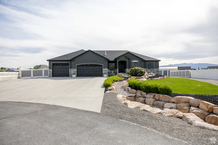 View of front of property with a garage, stone siding, concrete driveway, and stucco siding