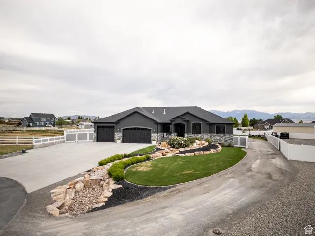 Ranch-style house with driveway, a garage, a mountain view, stone siding, and stucco siding