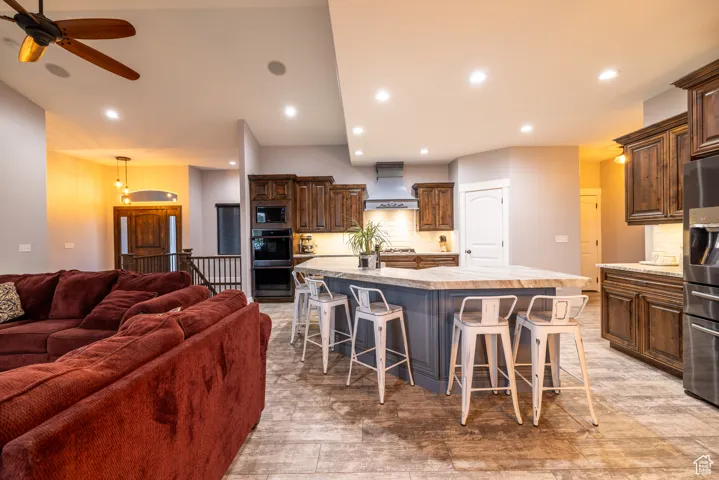 Kitchen featuring custom range hood, black appliances, open floor plan, light countertops, and a large island