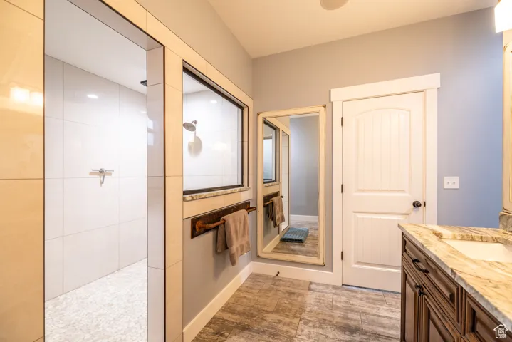 Bathroom featuring walk in shower, vanity, and wood finished floors