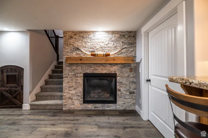 Living room featuring a stone fireplace, wood finished floors, stairway, and recessed lighting