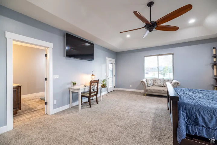 Bedroom with light carpet, recessed lighting, and a tray ceiling