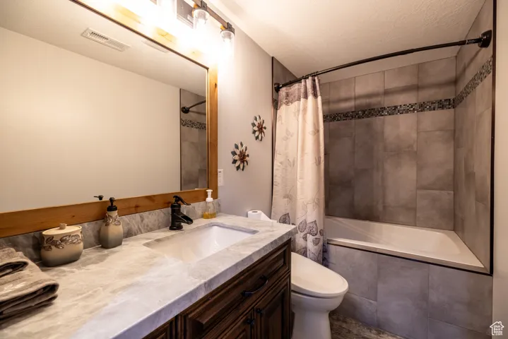 Full bath featuring vanity, tiled shower / bath combo, and a textured ceiling