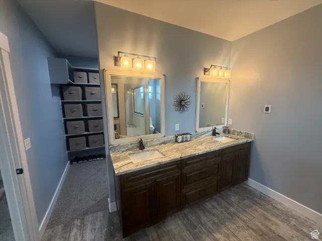 Bathroom featuring wood finished floors, double vanity, and a shower with shower door