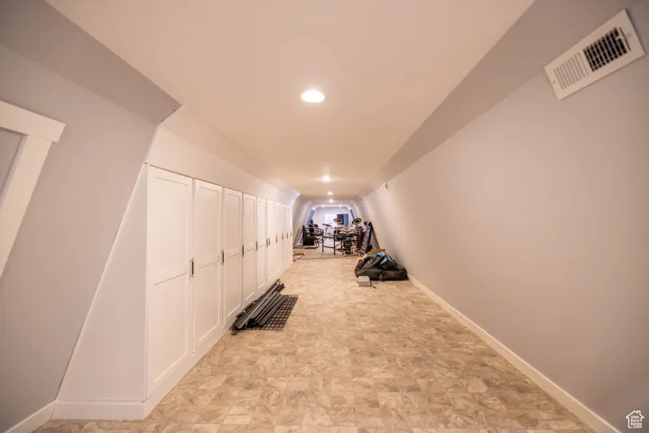 Exercise room featuring vaulted ceiling, recessed lighting, and stone finish flooring