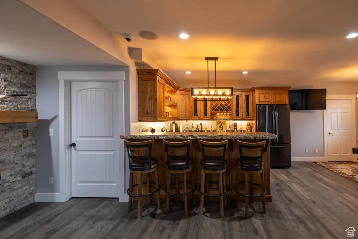 Indoor wet bar featuring freestanding refrigerator, dark wood-style flooring, pendant lighting, and recessed lighting