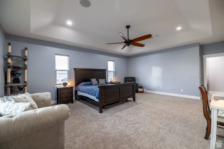Bedroom with a tray ceiling, recessed lighting, carpet floors, and ceiling fan