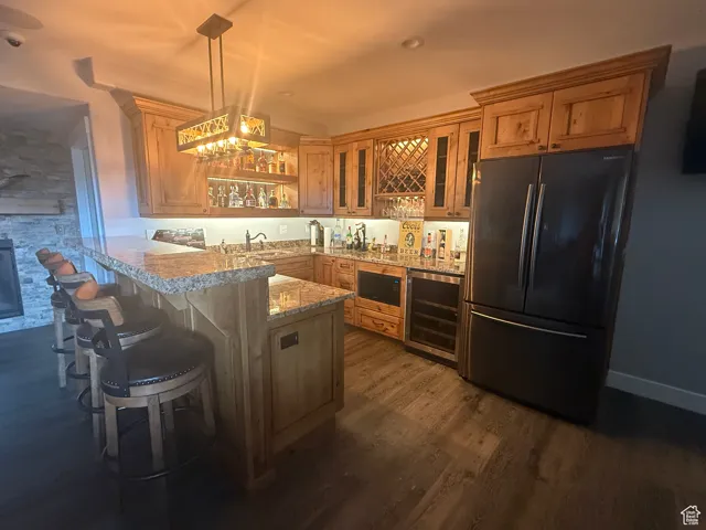 Kitchen with freestanding refrigerator, beverage cooler, a peninsula, built in microwave, and glass insert cabinets