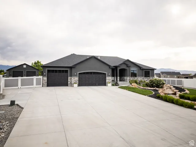 French country home with an attached garage, driveway, stucco siding, and stone siding