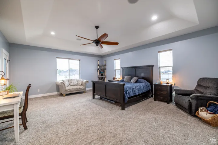 Bedroom with a tray ceiling, recessed lighting, light colored carpet, and ceiling fan