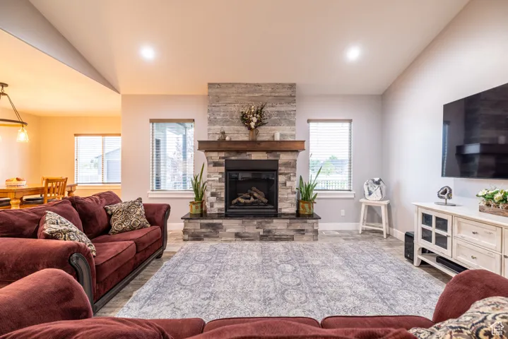 Living room with lofted ceiling, a stone fireplace, and recessed lighting