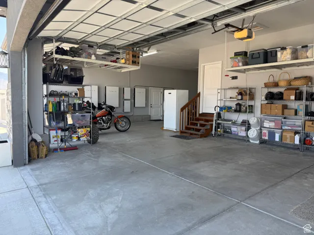 Garage featuring freestanding refrigerator and a garage door opener