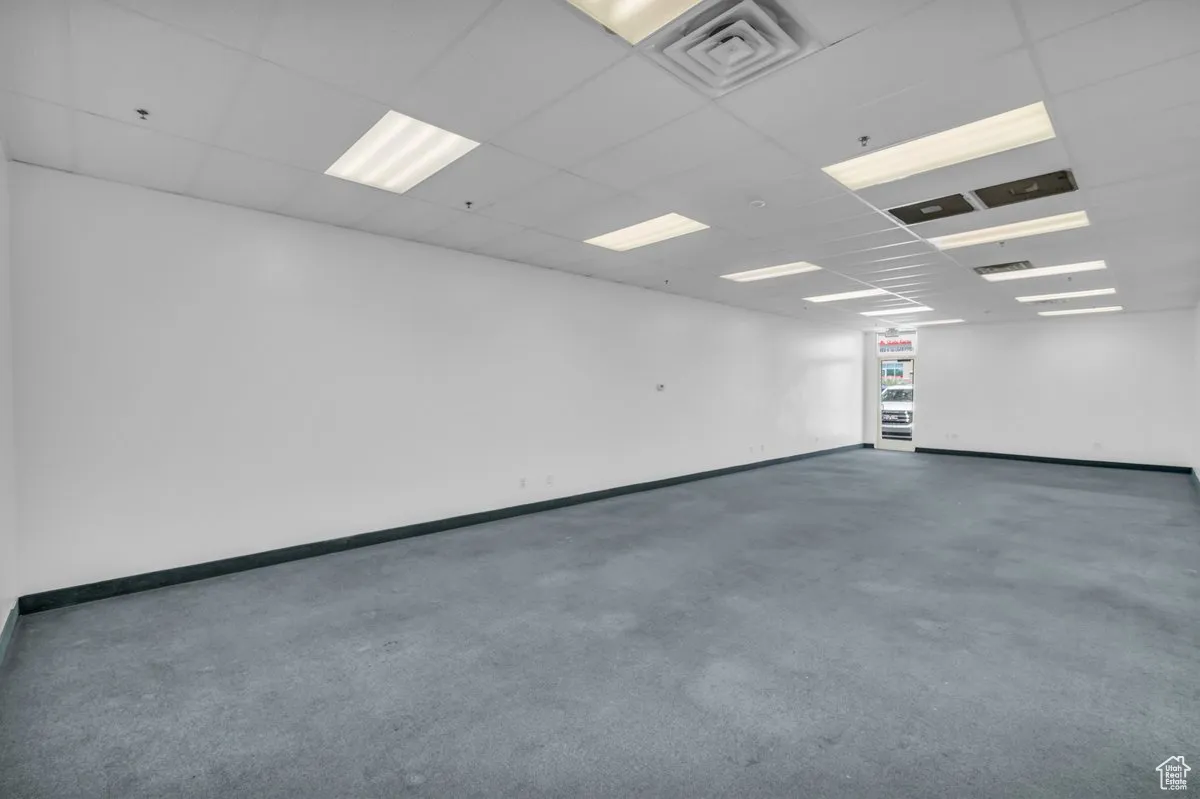 Spare room featuring carpet, a paneled ceiling, and a pendent fire sprinkler